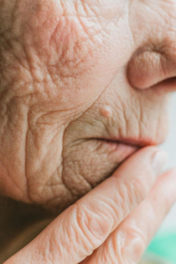 A old woman's face and hand close up.