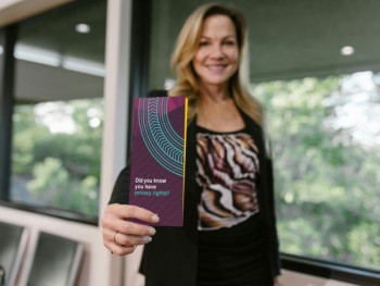 A woman in corporate clothes stands with her arm outstretched showing the privacy brochure