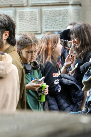 A group of teenagers. The focus is on a girl holding an energy drink and using her phone.