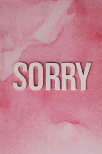 A pink piece of paper has the word 'sorry' on it in white cut out letters