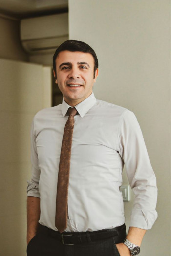 A man wears a shirt, pants, and a brown tie. He has short brown hair.