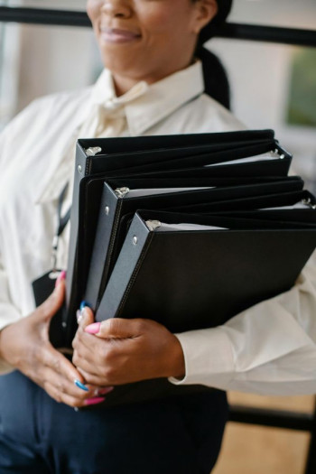 A woman holds three binders