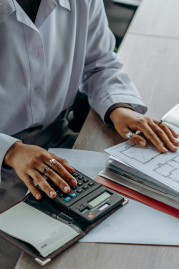 A close up of an accountant's hands resting on paperwork and a calculator