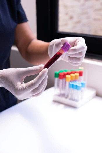 A pair of gloved hands hold a vial of blood.