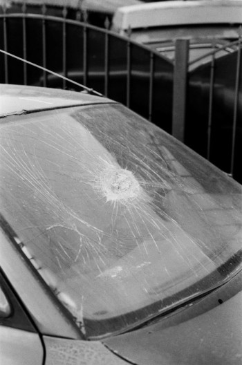 A black and white close up photo of a car with a chipped windscreen
