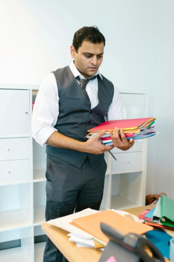 A man in a suit carries files.