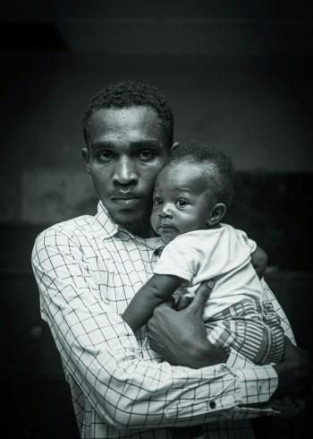 A man stands holding his child.