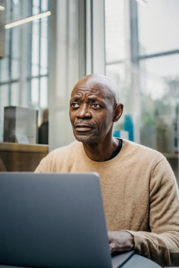 An older, bald black man sits using a computer