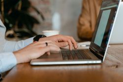 A woman's hands sit on a laptop