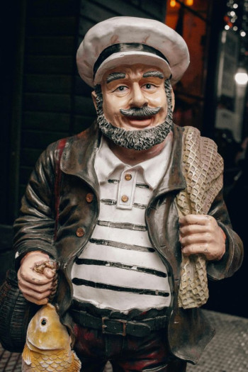 A model of a seaman with hat and beard where he is holding a fish