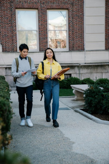 Two university students walk in front of a building