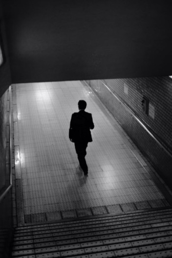 A man in shadow walks into an underground railway station.