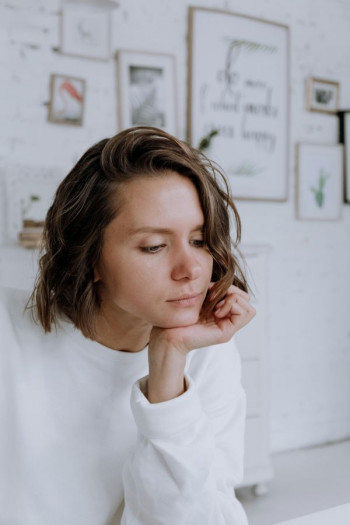A white woman with short light brown hair looks glum with her head in the heel of her hand.