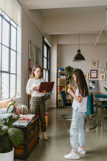 A woman and a young girl stand inside. The woman holds a laptop.