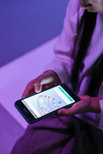 A child holds a phone in two hands and looks down at it.