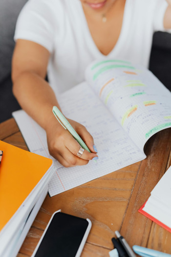 A person sits at a desk and writes in a grid lined notebook.