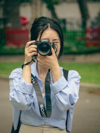 A dark haired woman holds a camera to her eye, taking a picture.