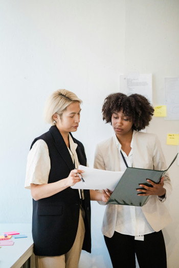 Two people look over paperwork on a clipboard.