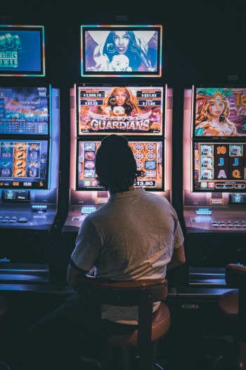 A person with short, dark hair sits in front of a slot machine.