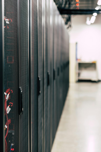 A line of computer servers stand in a server room.
