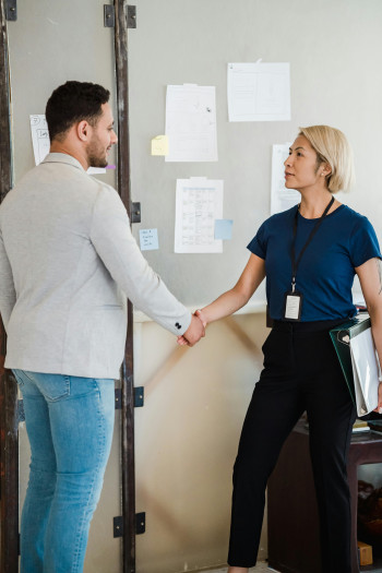 A man and a woman shake hands in an office setting.