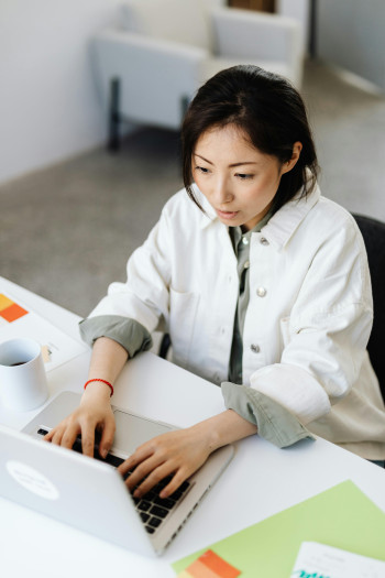 A woman works at her laptop while sitting at an office desk.